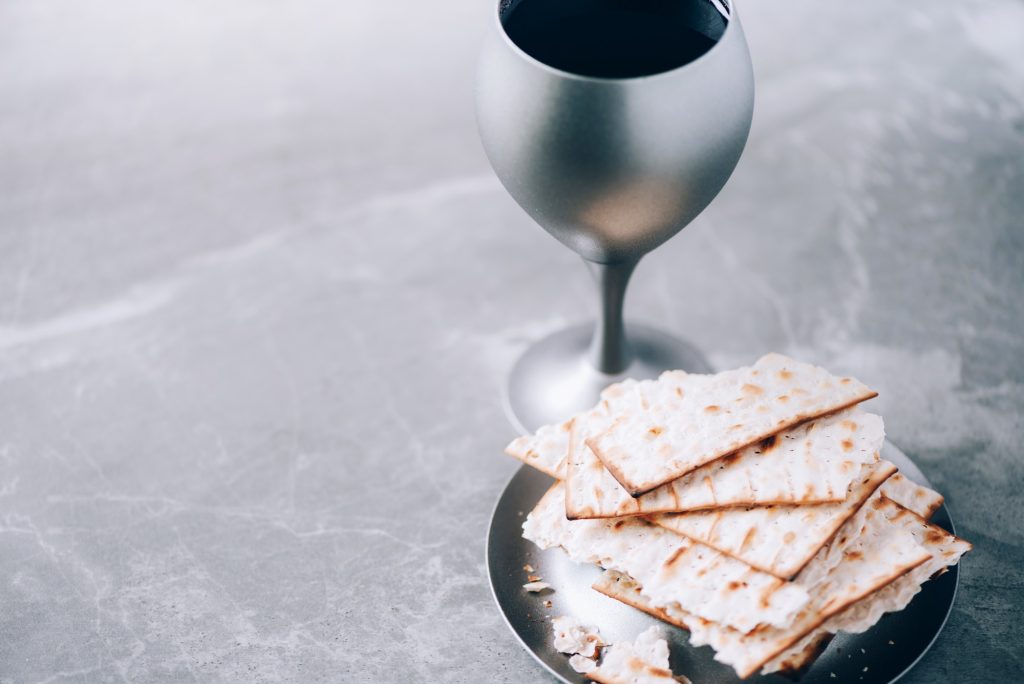 Communion still life. Unleavened bread, chalice of wine, silver kiddush wine cup on grey background